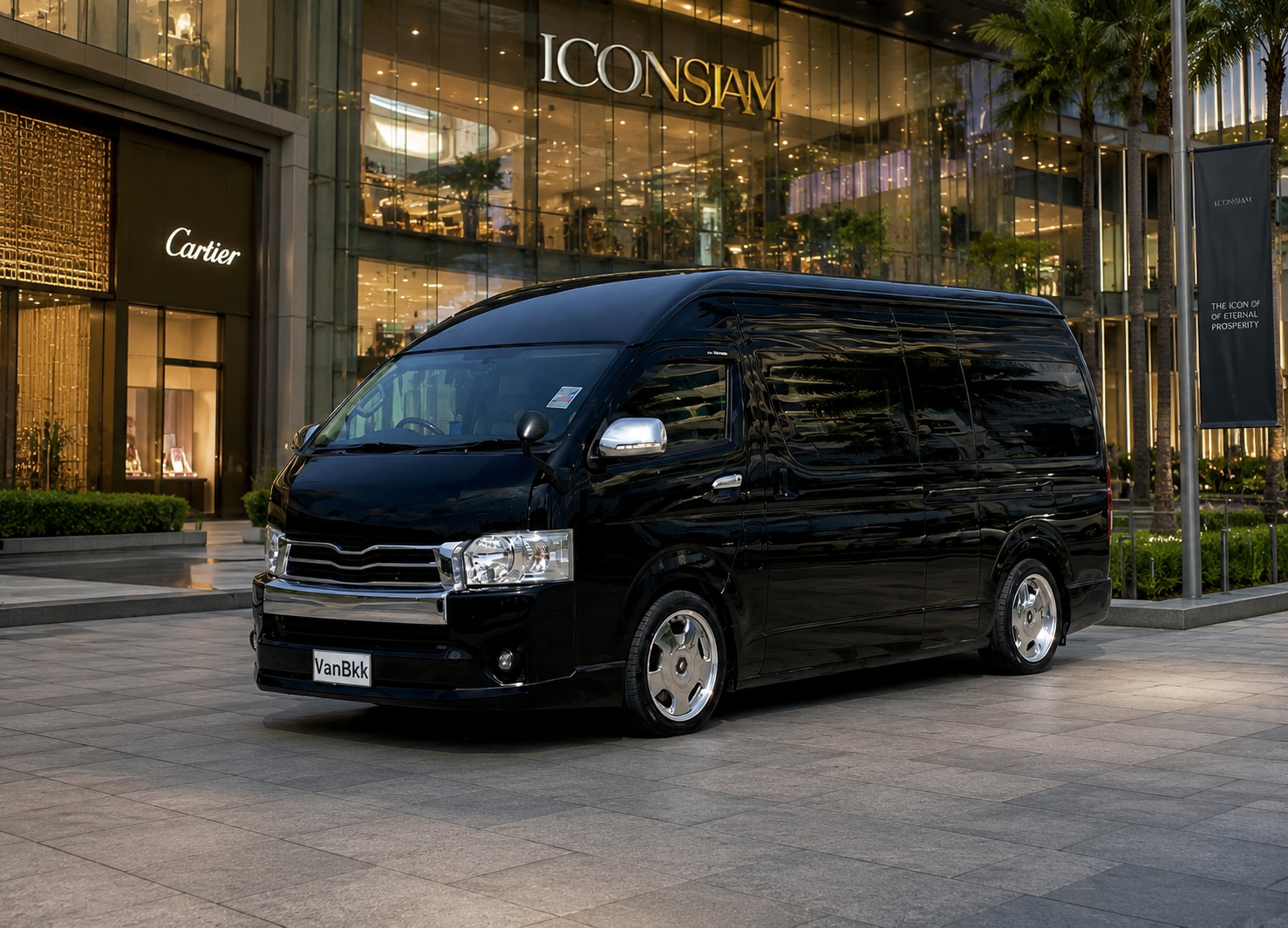 Black Toyota Commuter VIP van parked in front of a Bangkok luxury shopping district at sunset